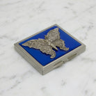Blue Enamel Butterfly Compact Mirror resting on white marble surface