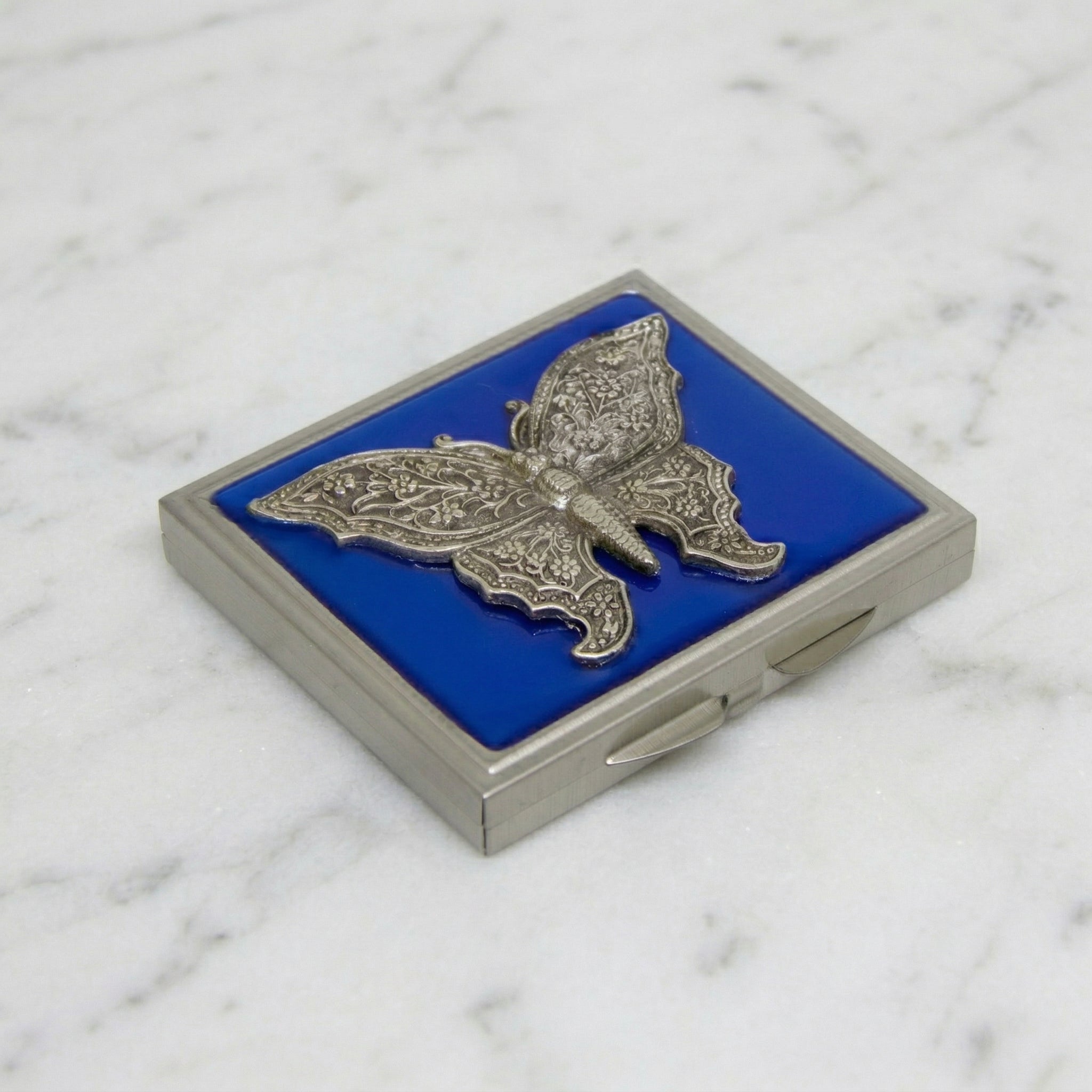 Blue Enamel Butterfly Compact Mirror resting on white marble surface