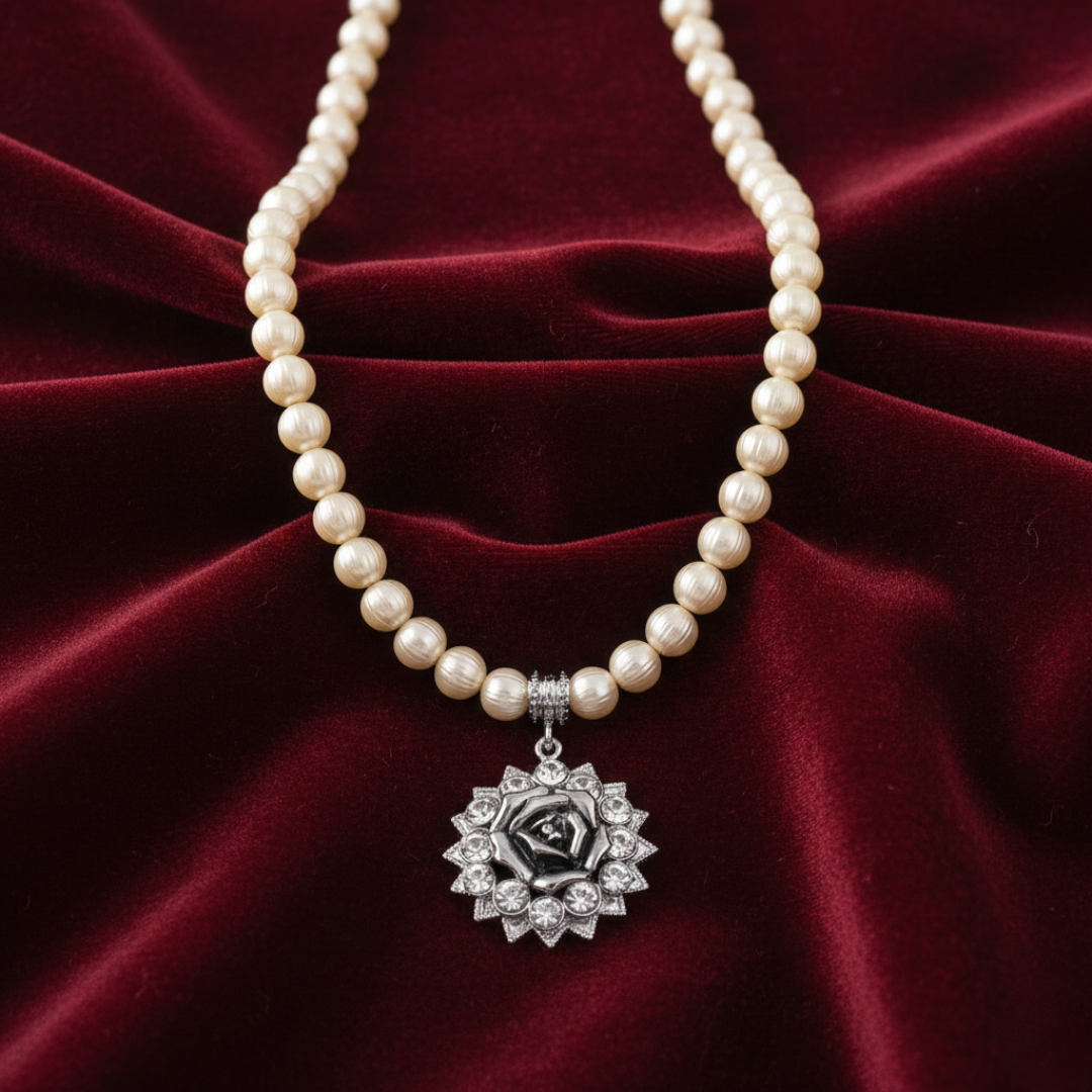 Pearl necklace with a silver floral pendant on a red velvet background
