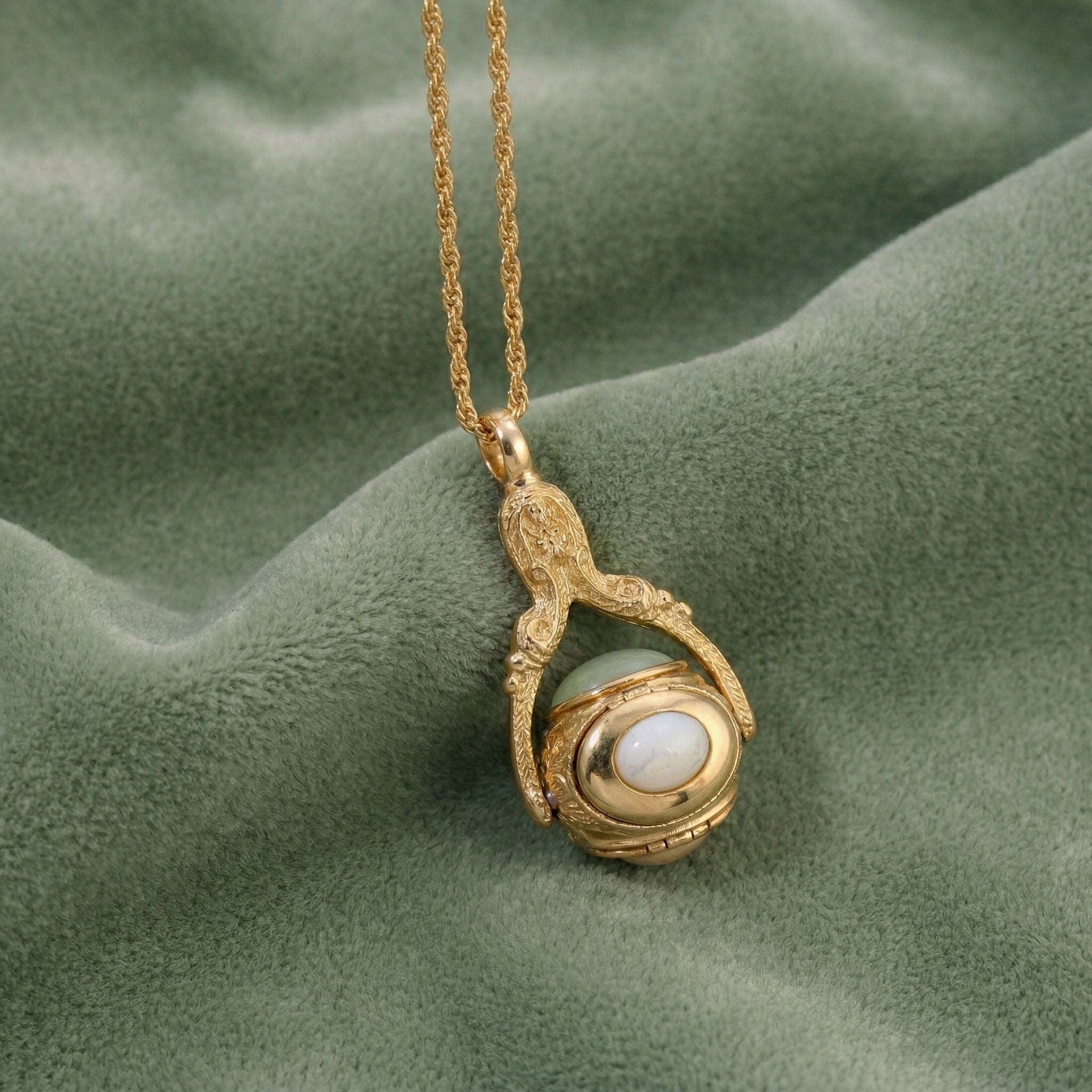 Gold necklace with a spinner gemstone pendant on a green fabric background