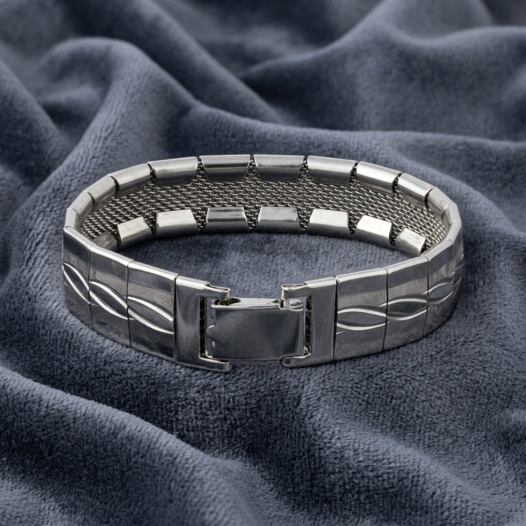 Silver bracelet with a mesh design on a textured blue fabric background