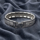 Silver bracelet with a mesh design on a textured blue fabric background