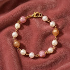 Gold tone pink peppermint and peach with white faux pearl beaded bracelet resting on dark pink fabric