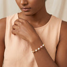 Woman in a light peach top wearing a pink peppermint and peach with white faux pearl beaded bracelet