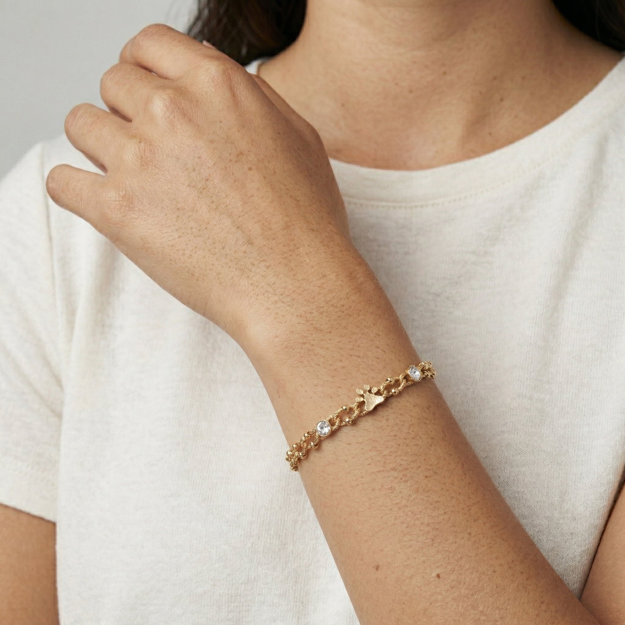 Woman in a white top wearing a gold tone Paws & Crystal Link Bracelet