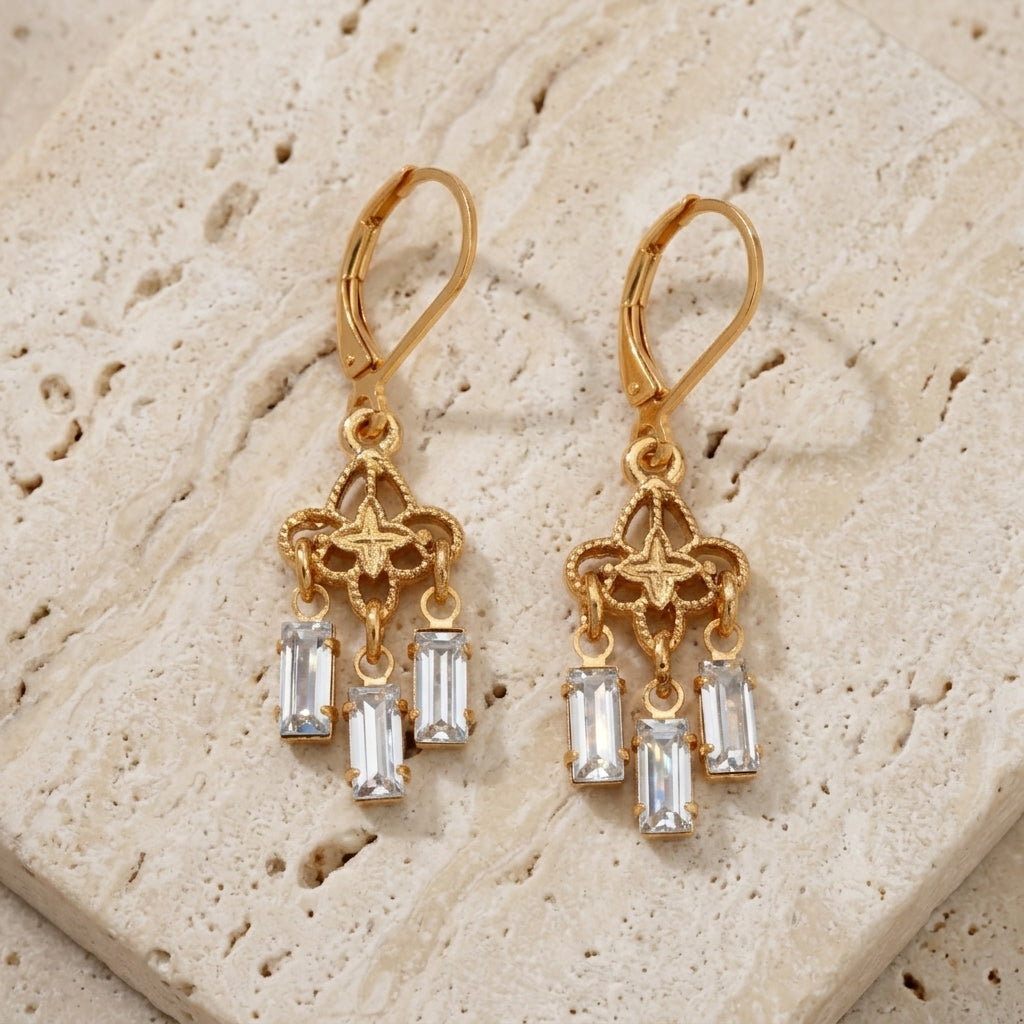 Gold Filigree & Crystal Drop Earrings resting on light colored stone