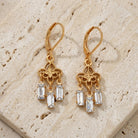 Gold Filigree & Crystal Drop Earrings resting on light colored stone