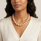 Woman in a white pinstriped top wearing a Round Champagne Faux Pearl Beaded Necklace 