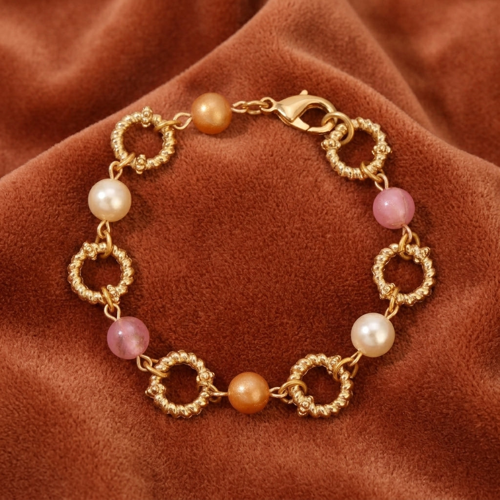 Gold bracelet with pearls and pink beads and pearls on a brown fabric background