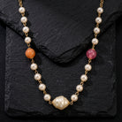 Pink & Peach Beaded Faux Pearl Necklace resting on a black stone surface