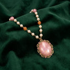 Golden Faux Pearl Beaded Peppermint Stone Pendant Necklace resting on dark green fabric