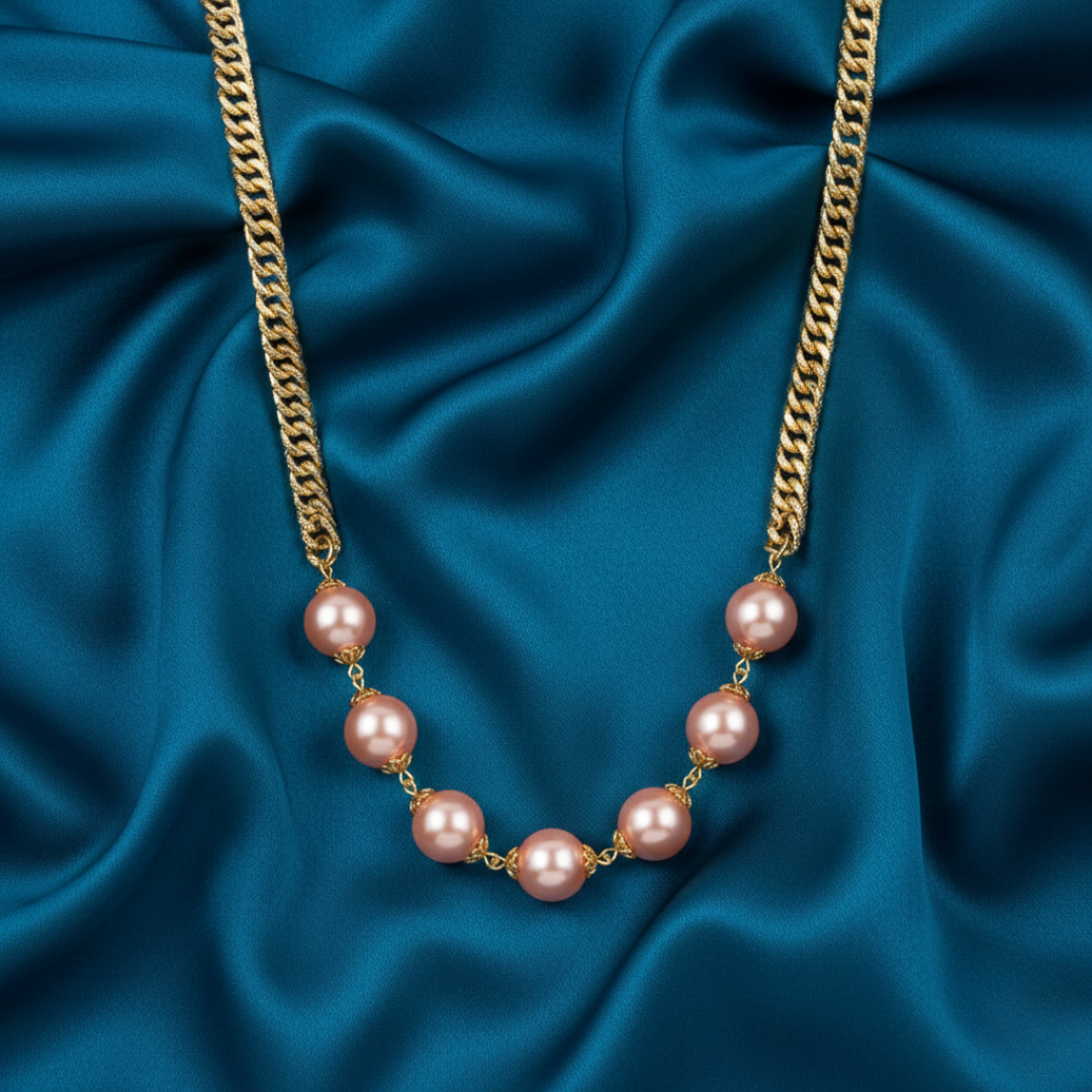 Pearl necklace with pink faux pearls on a gold chain against a blue satin fabric.