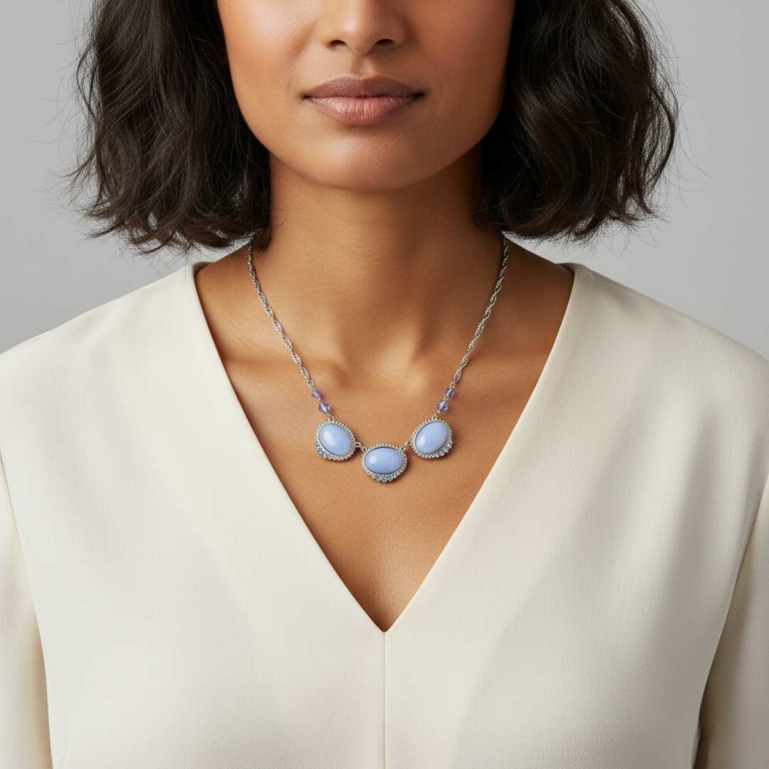 Woman wearing a necklace with three light blue gemstones against a neutral background