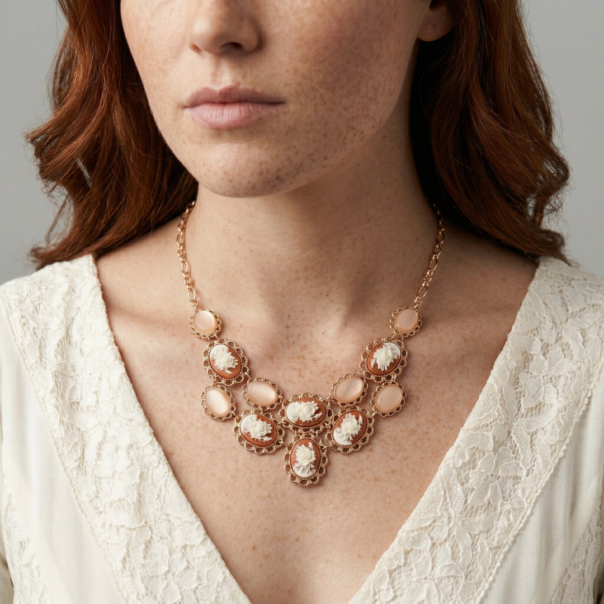 Woman in a white blouse top wearing a cameo rose bib necklace with peach colored stones