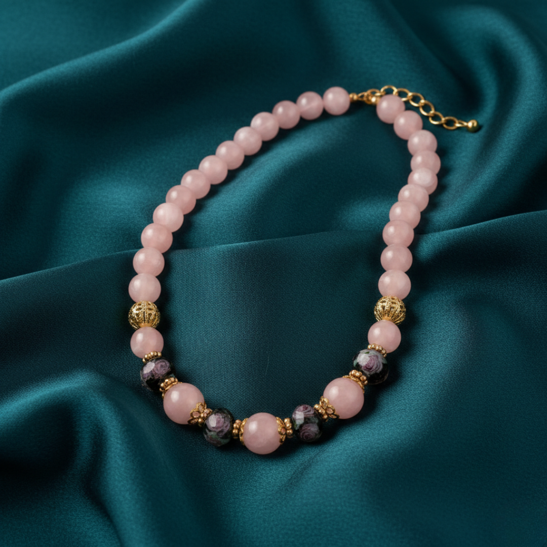 Rose pink beaded necklace on a light blue fabric background.