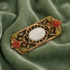 Decorative brooch with floral elements on a green fabric background