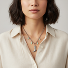 Necklace with cowboy boot pendant and turquoise stones worn by a person in a beige shirt.