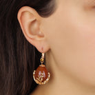 A close-up of a model's ear wearing a Golden Vintage Style Carnelian Egg & Topaz Crystal Drop Earrings