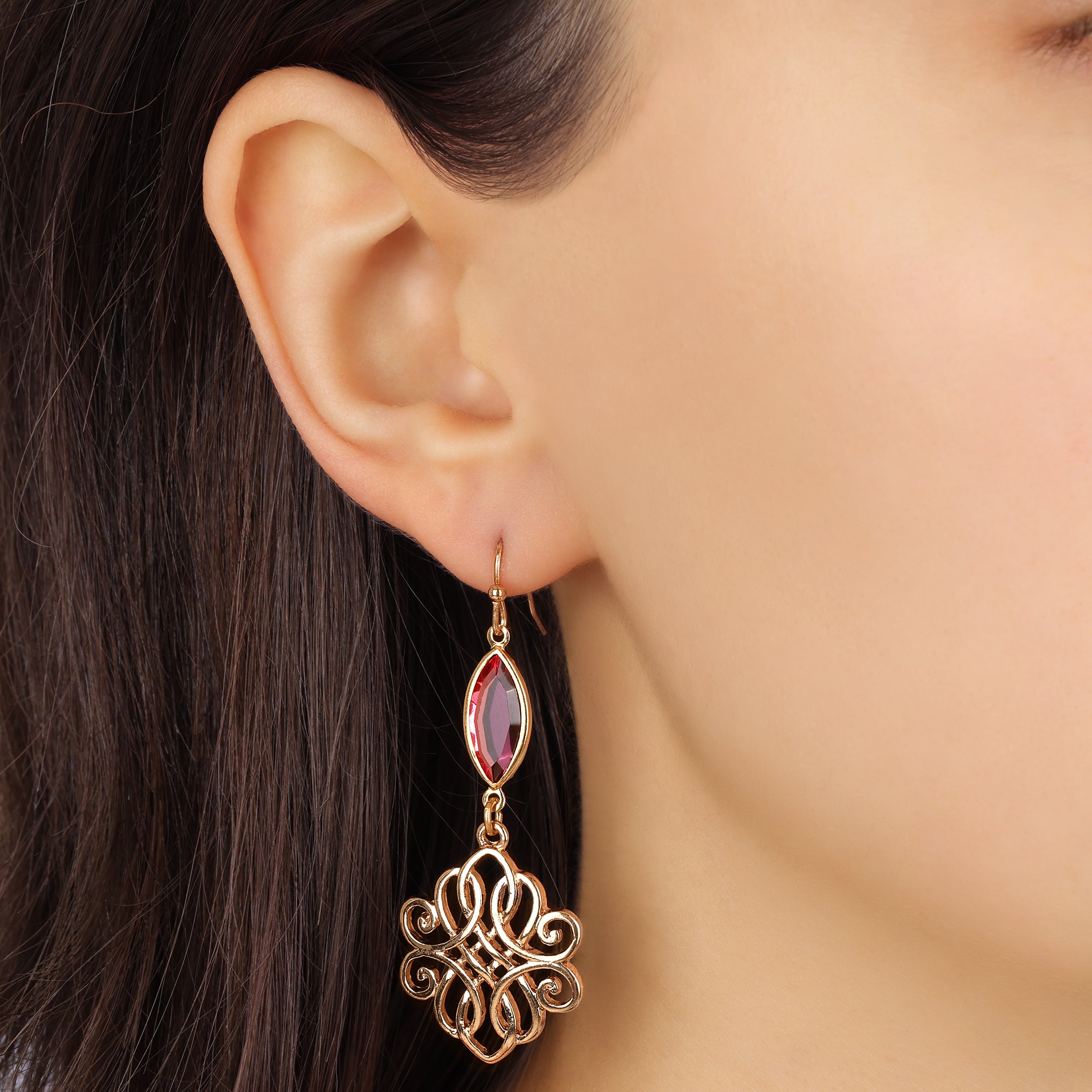Gold earring with a rose gemstone worn by a model with dark hair.