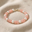 Peach Cracked Glass & White Faux Pearl Beaded Bracelet resting on beige linen