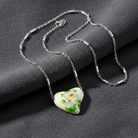 Necklace with a heart-shaped pendant featuring a white rose design on a dark surface