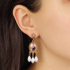 A close-up of a woman's ear wearing Oval Pink And Purple Floral Manor House & Faux Pearl Teardrop Dangle Stud Earrings