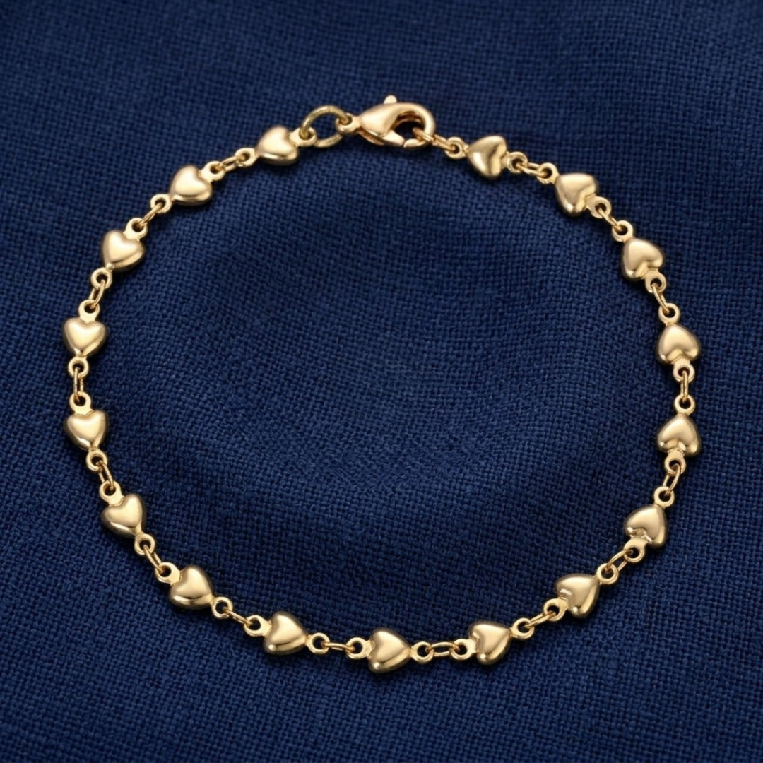 Classic Golden Heart Link Chain Bracelet displayed on a textured dark blue fabric background.