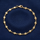 Classic Golden Heart Link Chain Bracelet displayed on a textured dark blue fabric background.