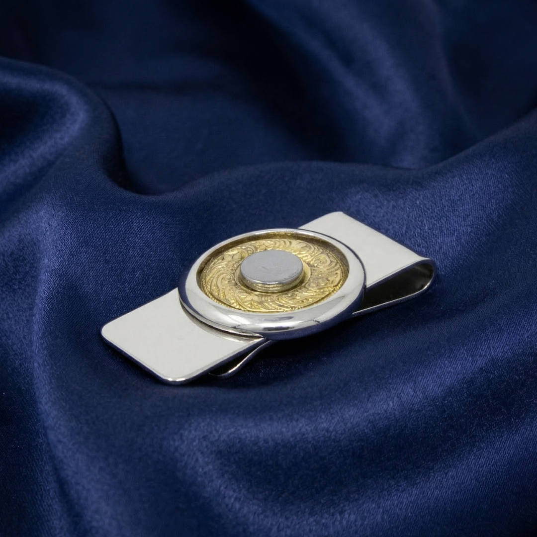 Round silver and hematite money clip resting on a navy blue satin fabric background