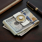 Round silver and hematite money clip holding together a stack of US $100 bills on a desk
