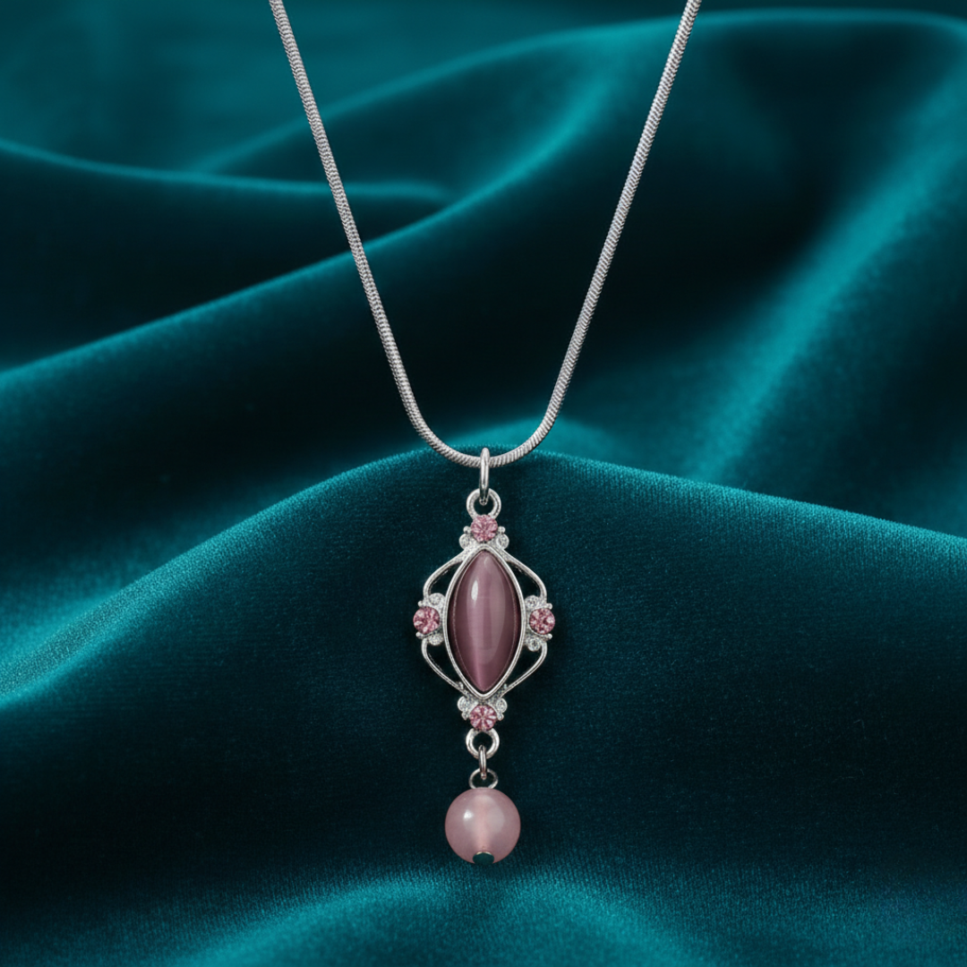 Necklace with a pink pendant on a teal fabric background