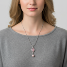 Woman wearing a silver necklace with a pink pendant against a neutral background