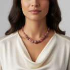 Woman wearing a pink pearl necklace against a neutral background