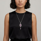 Woman in a black sleeveless top wearing a purple stone drop pendant necklace