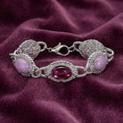 Silver tone and purple stone bracelet resting on purple fabric 