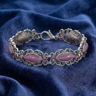 Silver bracelet with pink stones on a blue fabric background