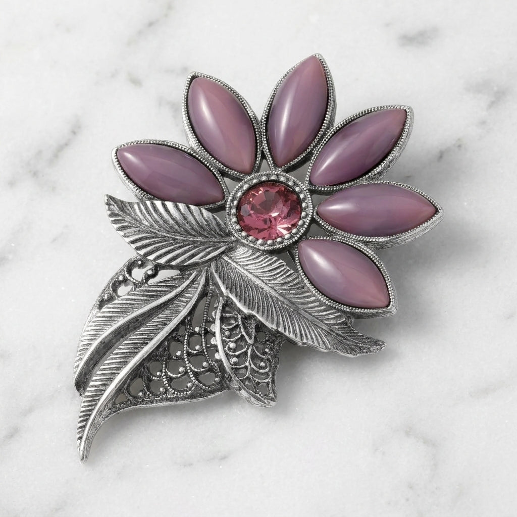 Decorative brooch with amethyst gemstones and silver leaves on a marble background