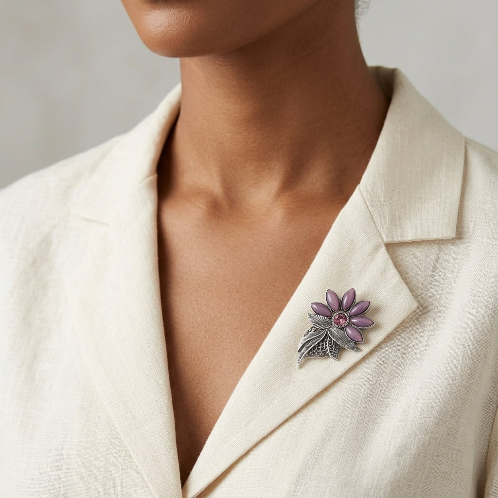 Person wearing a white blazer with a decorative brooch on a neutral background