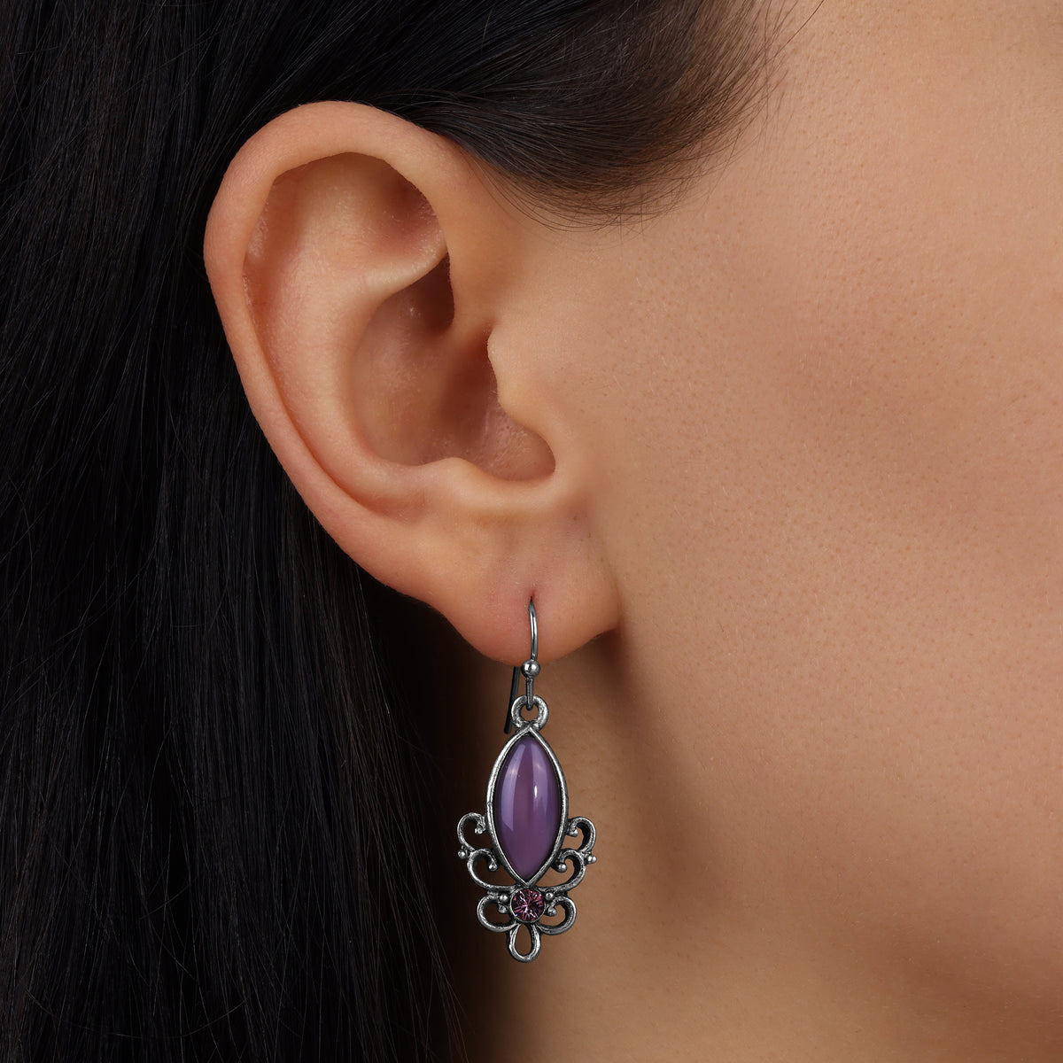 A close-up of a model's ear wearing a Royal Filigree Amethyst Moonstone Drop Earrings
