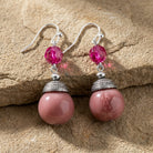 Purple amethyst earrings with silver hooks and beads on a stone surface