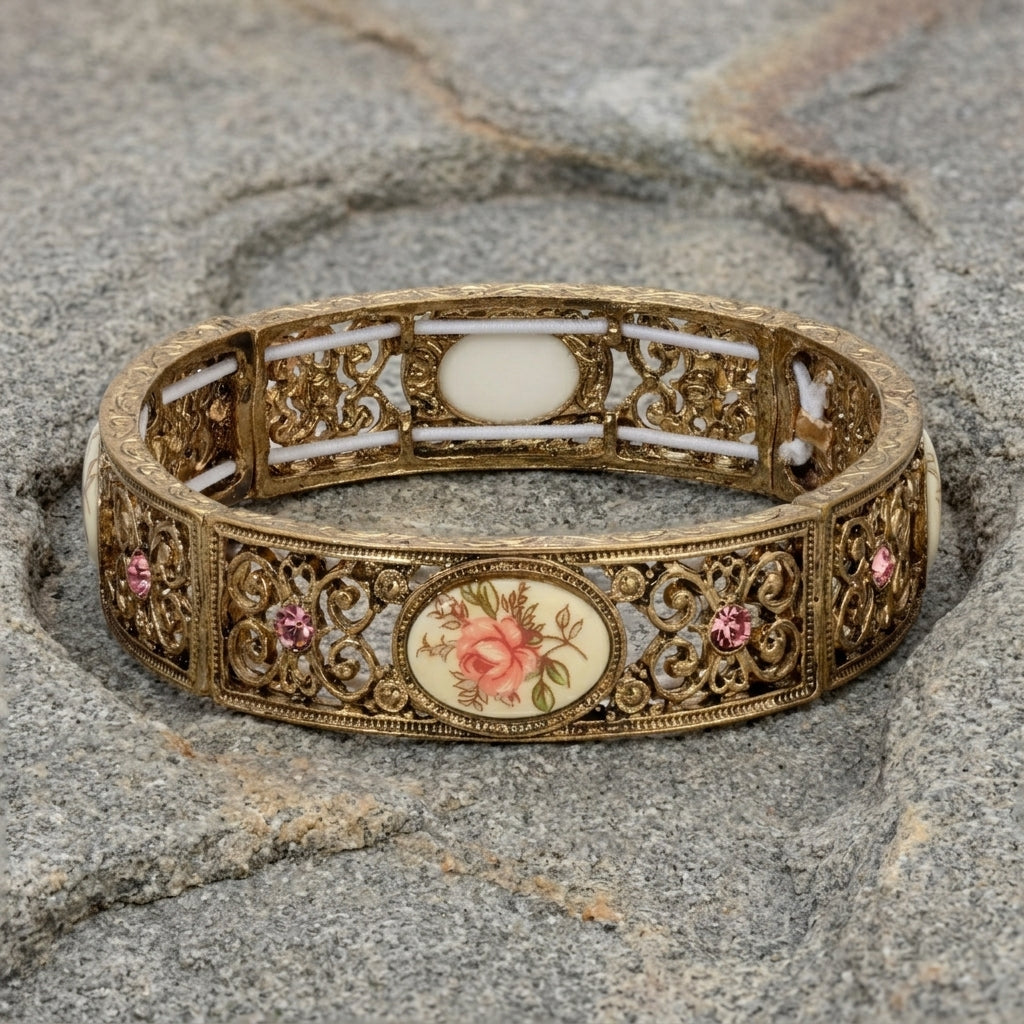 Decorative gold bracelet with floral design on a stone surface