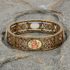 Decorative gold bracelet with floral design on a stone surface