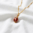 Trellis Red Enamel Crystal Egg Drop Pendant Necklace 18" resting on white cloth
