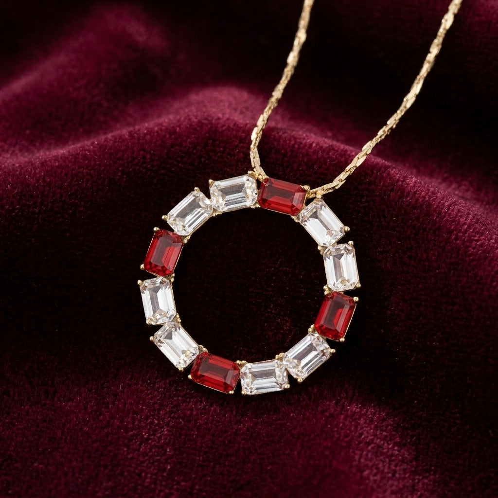Gold necklace with a circular pendant featuring red and clear crystals on a maroon fabric background