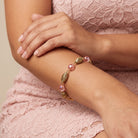 Woman in a laced pink dress wearing a Light Rose Pink AB Crystal & Gold Corrugated Bead Bracelet on her wrist