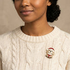 Woman in a white sweater wearing a puppy in a Santa outfit brooch pin
