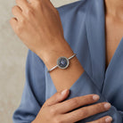Woman in a blazer wearing a blue pave crystal silver tone spring hinge bracelet on her wrist