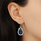 A close-up of a model's ear wearing a Silver & Crystal Loop Sapphire Bead Drop Earrings