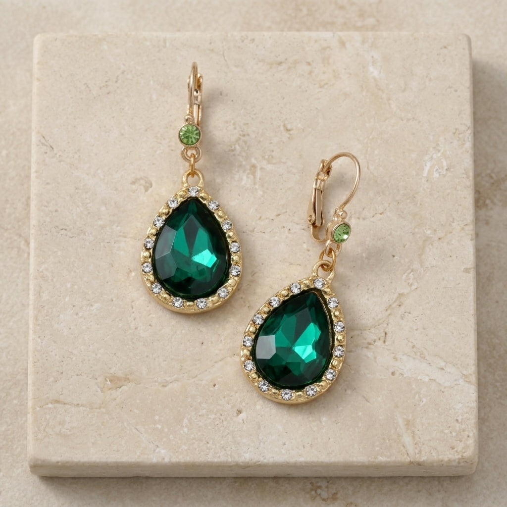 Crystal Radiance Pear Shape Green Crystal Drop Earrings displayed on a beige stone tile.