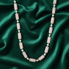Necklace with pink beads and pearls on a green satin background